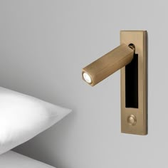 a light that is on the side of a wall next to a pillow and pillows