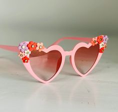 Pink heart-shaped sunglasses with pastel clay flowers and hearts with Kundan details  Category 3: General purpose sunglasses. High protection against sunglare. Good UV protection. Not suitable for driving at night. Includes black hardshell case and lens cloth **please handle with care** Heart Shaped Sunglasses With Uv Protection For Spring, Cute Sunglasses With Gradient Lenses For Spring, Cute Heart Shaped Sunglasses For Spring, Cute Spring Sunglasses With Gradient Lenses, Cute Spring Sunglasses With Tinted Lenses, Cute Pink Sunglasses For Spring, Cute Pink Polarized Sunglasses, Pink Sunglasses With Gradient Lenses For Spring, Pink Gradient Sunglasses For Spring