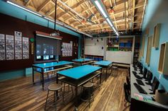 an empty classroom with blue tables and chairs