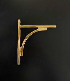 a brass shelf bracket on a black wall with the top half turned to look like it is