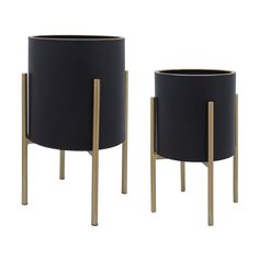 two black planters sitting next to each other on metal legs with gold trimmings