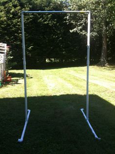 an empty soccer goal in the middle of a yard with trees and grass behind it