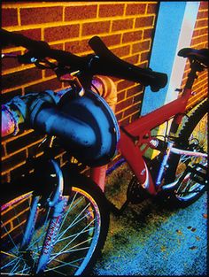 a red bike parked next to a brick wall with blue trim on it's rims