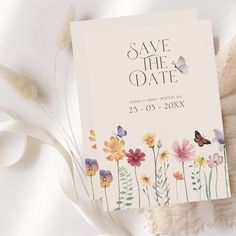 an image of save the date card with flowers and butterflies on it next to feathers