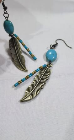 two earrings with beads and feathers hanging from them