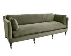 a green velvet couch with two pillows on it's arms and legs, against a white background