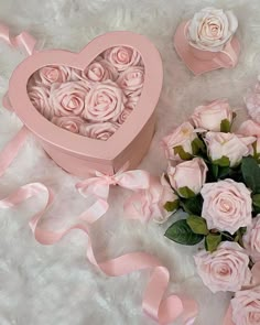 pink roses are in a heart shaped box next to a bouquet of flowers and ribbon