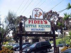 a sign for a little mexican restaurant with cars parked in the parking lot behind it