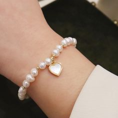 This pearl bracelet features a delicate heart-shaped mother-of-pearl pendant, creating a captivating combination of elegance and romance. The combination of the radiant pearls and the ethereal beauty of the mother-of-pearl pendant makes this bracelet a truly enchanting accessory. It exudes a sense of grace and sophistication, while the heart-shaped motif symbolizes love, making it a perfect gift for someone special or a cherished addition to your own jewelry collection.Plating Color: Yellow Gold Elegant Charm Bracelet With Pearl And Round Beads, Delicate Pearl Pendant Bracelet As Gift, Dainty Pearl Bracelet With Pendant As Gift, Feminine Pearl Bracelets With Pearl Charm, Elegant Heart Charm Bracelet For Mother's Day, Elegant Heart Charm Bracelet For Wedding, Elegant White Heart Bracelet For Valentine's Day, Pearl White Oyster Bracelet As A Gift, Heart-shaped Pearl Bracelet For Wedding