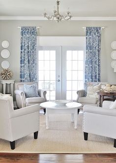 a living room with white furniture and blue drapes on the window sills