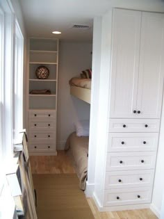 an open door leading to a bedroom with white cabinets and drawers on either side of the room