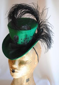 This seductive evening mini top hat is an excellent choice for any dark cabaret event. It is covered with a rich emerald green(pictured) or black thick satin fabric and embellished with various black trimmings. A curled black ostrich feather, dotted black tulle, chic black stripped rooster feathers and a glorious black beaded button. For sparkling burlesque style appearances! Measurements : height 4 inches( 10 cm ) front to back 9 inches ( 22 cm ) side to side 7.5 inches ( 19 cm ) This mini top Adjustable Short Brim Top Hat For Carnival, Fitted High Crown Hat For Carnival, Fitted High Crown Costume Hat For Carnival, Short Brim Top Hat For Carnival Party, Curved Brim Top Hat For Kentucky Derby Costume, Fitted Flapper Costume Hats And Headpieces For Party, Fitted Steampunk Party Hat, Adjustable Steampunk Party Hat, Steampunk Party Costume Hat Fitted