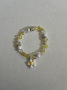 A yellow and white flower bracelet Cheap Yellow Flower Shaped Beaded Bracelets, Spring White Beaded Bracelets With Flower Charm, White Beaded Bracelets With Flower Charm For Spring, White Flower-shaped Jewelry For Summer, White Floral Jewelry For Summer, Handmade White Beaded Bracelets For Spring, Cute White Flower Bracelets, White Stretch Bracelet For Spring, Spring White Adjustable Stretch Bracelet