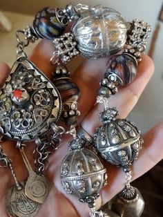 An assemblage of Yemen wedding globe beads, one is hallmarked, and a pear shaped fibula pendant from Siouan Ouan region in Morocco. These are rare hard to find silver pendants. The central stone I think is not real coral. It has three original silver and niello charm pendants on original chains, one was missing, so I've added a Berber silver evil eye charm. Handmade chain using sterling wire with Yemen berry beads, (silver content unknown), faceted pyrite, silver beads from India, silver plated Ceremonial Silver Jewelry With Large Pendant, Unique Ceremonial Jewelry With Silver Beads, Silver Jewelry With Large Pendant For Ceremonial Occasions, Unique Silver Beads Pendant Jewelry, Unique Silver Beaded Pendant Jewelry, Silver Polished Beads Jewelry For Celebration, Teardrop Silver Beads Metal Jewelry, Celebration Silver Jewelry With Polished Beads, One-of-a-kind Silver Jewelry For Festivals