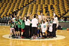 a group of young people standing on top of a basketball court holding hands in the air