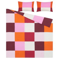 an orange, pink and white bed spread with matching pillow cases on top of it