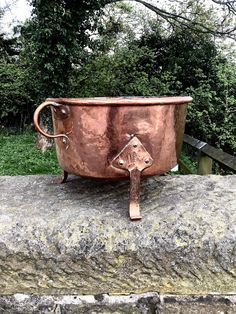 a large metal pot sitting on top of a stone wall