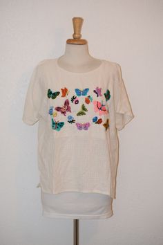 "Sweet little vintage top will have your ready for dancing and having fun in the summer breeze. Creamy gauzy muslin peasant ethnic summer top / blouse with short fluttery sleeves and embroidered colorful butterflies was made in Guatemala.  So sweet for any summer occasion.  Free of rips, stains and odor. Women's oversize medium to large Back of neck to bottom of blouse:  25\" Shoulder to shoulder at back:  22\" Top of sleeve to bottom hem:  7\" Armpit to armpit:  24\" Under arm seam:  17\" Side to side at waist:  21 1/2\" Side to side at bottom:  22\" For a variety of vintage goodies, check out my shop @: https://www.etsy.com/shop/RagandBonesFinds For a unique pillow fashioned from my treasure trove of vintage fabrics, visit my shop @: https://www.etsy.com/shop/VintagePulledThreads" Spring Bohemian Crew Neck Blouse, Multicolor Embroidery Short Sleeve Tops For Festival, Short Sleeve Cotton Embroidered Top For Festivals, Short Sleeve Tops With Motif For Summer, Multicolor Peasant Tops With Short Sleeves, Casual Beach Peasant Top With Floral Embroidery, Spring Folk Blouse For Vacation, Folk Style Cotton Tops For Spring, Bohemian Short Sleeve Top With Multicolor Embroidery