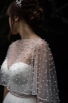 the back of a woman's wedding dress with pearls on it