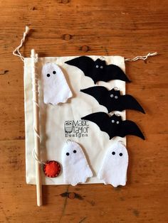 three halloween decorations on a wooden table with bats and ghostes hanging from the string