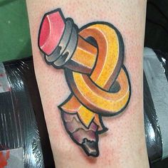 a tattoo on the leg of a person with a pencil and an orange ribbon around it