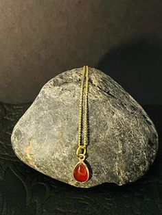 Carnelian is a gemstone known for its warm and fiery orange-red color. The drop pendant design adds an elegant and sophisticated touch to the necklace. Brass is a durable and affordable metal that complements the vibrant hue of the Carnelian. This necklace can be a statement piece, perfect for adding a pop of color and personality to any outfit. It can be worn for both casual and formal occasions, and its warm tones make it particularly suitable for autumn and winter seasons. 18" necklace Carnelian Cabochon Necklaces For Jewelry Making, Gold Carnelian Pendant Necklace, Orange Carnelian Gemstone Necklace, Red Teardrop Gemstone Necklace, Orange Gemstone Pendant Necklace, Orange Cabochon Pendant Necklace, Red Oval Carnelian Necklace, Carnelian Gemstone Drop Jewelry, Red Carnelian Oval Necklace