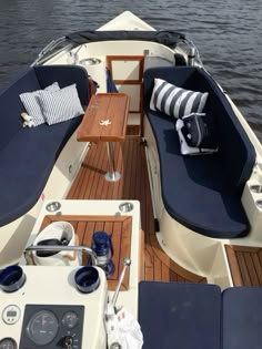 the inside of a boat with blue cushions and pillows on it's back end