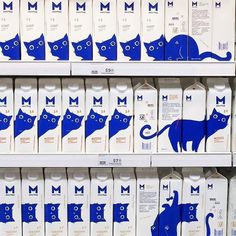 milk cartons with blue cats on them in a grocery store display case, one for milk and the other for milk