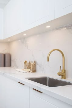 a kitchen with marble counter tops and gold faucets on the sink's side