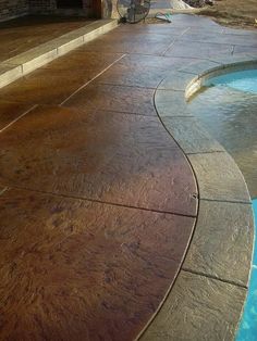 an empty swimming pool in front of a brick wall and stone steps with water running down the side