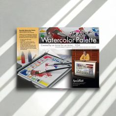 an advertisement for watercolor palettes is displayed on a table with paintbrushes