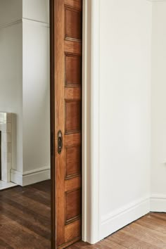 an open door in a white room with hardwood floors