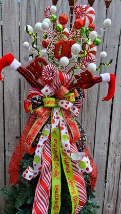 a christmas tree decorated with candy canes and decorations on top of a wooden fence