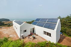 a house with solar panels on the roof and some people sitting in chairs near it