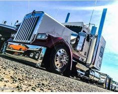 a large semi truck parked on top of a dirt field next to a boat trailer