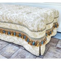 an upholstered footstool with tassels and beads on the sides