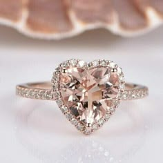 an engagement ring with a heart shaped morganite in the center and diamonds surrounding it