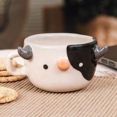 a mug with a cow's head on it sitting next to crackers