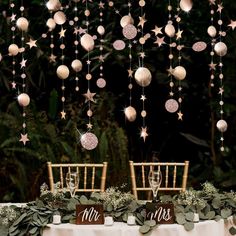 the table is set up for a wedding reception with white and pink decorations hanging from the ceiling