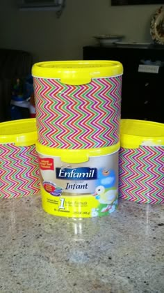 three plastic containers sitting on top of a counter next to a yellow container with white and pink designs