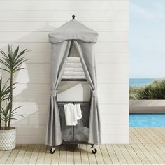 a gray canopy bed next to a pool with towels on the rack and a potted plant