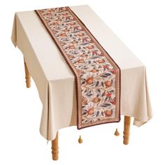 a table with a white cloth on it and an orange flower design at the top