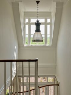 a light fixture hanging from the ceiling in a room with white walls and wooden stairs