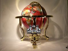 a golden stand with a red and white globe on it's top, holding two keys