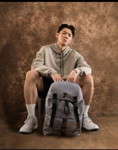 a man sitting on a chair with a backpack in front of him and his legs crossed