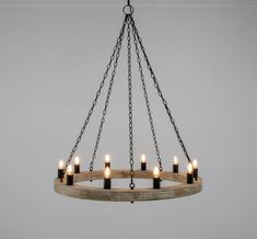 a wooden chandelier with candles hanging from it's center and chain around the light fixture