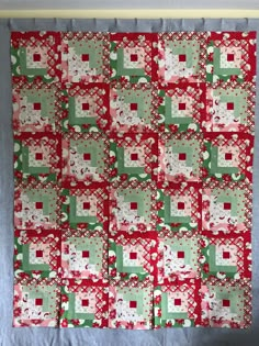 a red and green quilt hanging on the wall