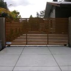 a wooden fence is in front of a concrete block area with trees and bushes behind it