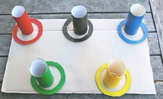 four different colored spools sitting on top of a white board with rings around them