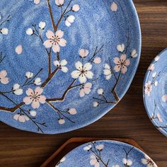 three plates with flowers painted on them sitting on a wooden table next to each other